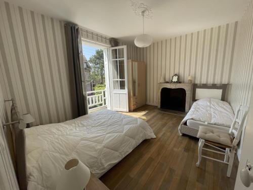 - une chambre avec un lit, une cheminée et une fenêtre dans l'établissement Villa spacieuse à Cabourg, 200m plage, jardin, 5 chambres, parking, ménage inclus - FR-1-487-359, à Cabourg