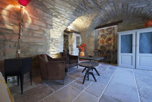 a room with a table and chairs and a stone wall at La Maison du Passage - Chambres - Suites premium, Spa, Piscine et Restaurant in Martignargues