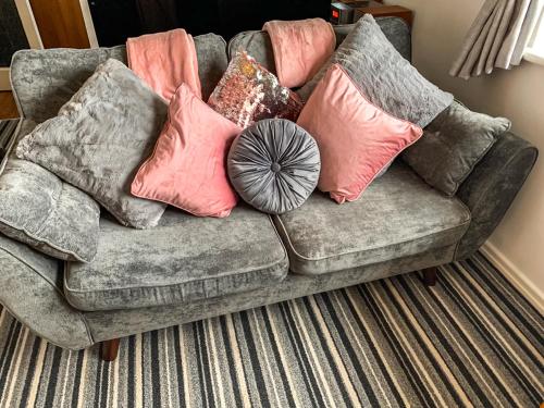 a couch with pillows on it in a living room at Sunny Rhyl Apartment - Uk44631 in Rhyl
