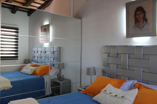 um quarto com 2 camas com lençóis azuis e almofadas laranja em Apartment in the city of Olot Penthouse em Olot