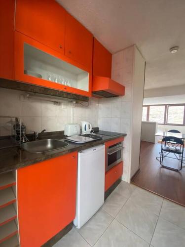 uma cozinha com armários laranja e um lavatório em El Colorado, Farellones. em Santiago