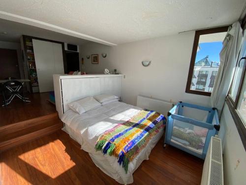 um quarto com uma cama com um cobertor colorido em El Colorado, Farellones. em Santiago