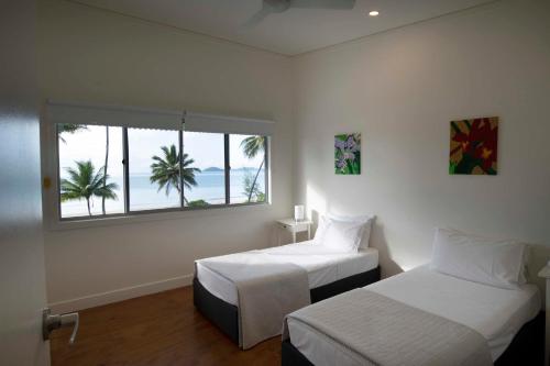 - une chambre avec 2 lits et une fenêtre avec des palmiers dans l'établissement Bella's Beach House - Family Home - South Mission Beach, à South Mission Beach
