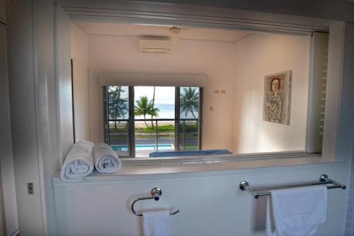 La salle de bains est pourvue d'un miroir et d'un lavabo avec des serviettes. dans l'établissement Bella's Beach House - Family Home - South Mission Beach, à South Mission Beach