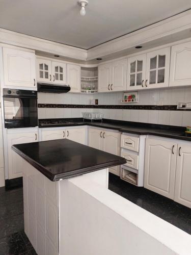 a kitchen with white cabinets and a black counter top at Casa Estación Modelia, near to the airport. in Bogotá