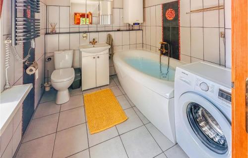 a bathroom with a tub and a toilet and a washing machine at 3 Bedroom Lovely Home In Nowe Warpno in Nowe Warpno