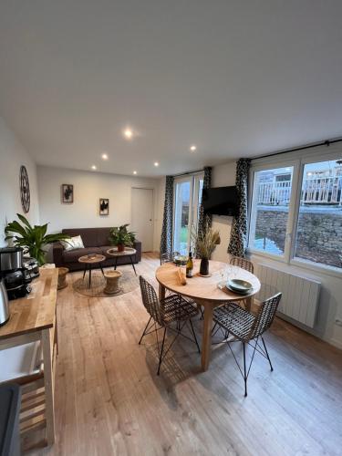 een woonkamer met een tafel en stoelen en een bank bij Beau Loft room proche mont saint Michel jaccuzi illimité en plein centre Avranches in Avranches