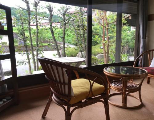 Habitación con 2 sillas, mesa y ventana en Pension Amagiji, en Izu
