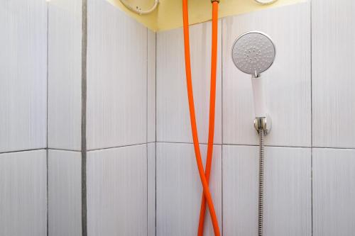 une douche avec des cordons orange suspendus à un mur dans l'établissement RedDoorz near Tirtonadi Park Solo, à Kadiporo