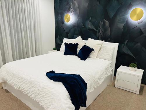 Un dormitorio con una gran cama blanca con almohadas azules. en Skylight Splendour!, en Perth