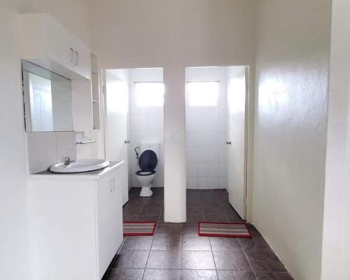 a white bathroom with a toilet and a sink at Mohans Apartments in Nausori