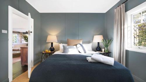 a bedroom with a bed with blue walls and two lamps at Werona Cottage - enchanting home in Burrawang