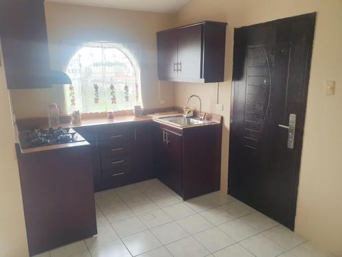 a kitchen with brown cabinets and a sink and a window at Confort in Manta