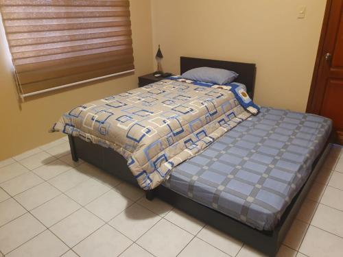 a bed with a blue comforter in a bedroom at Confort in Manta