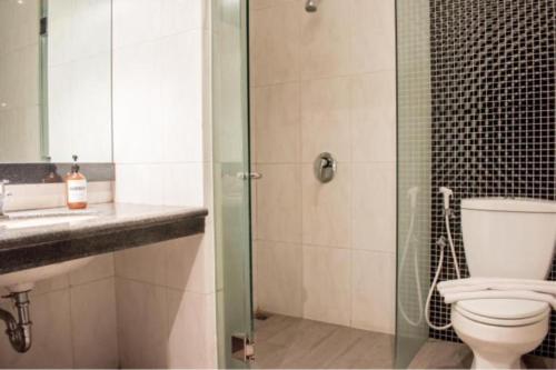 a bathroom with a toilet and a glass shower at Luminor Hotel Jember By WH in Jember