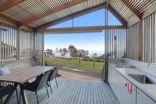 a large deck with a table and chairs and a kitchen at Reflections Bonny Hills - Holiday Park in Lake Cathie