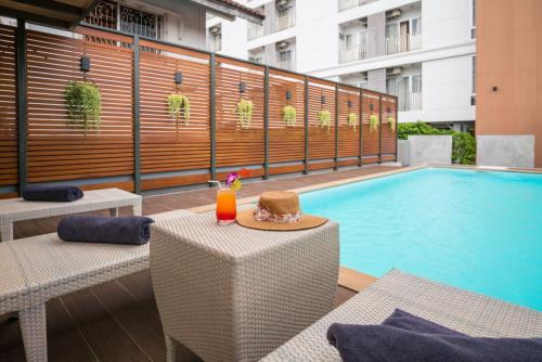 a table with a hat next to a swimming pool at Blue Hippo Hotel in Ban Khlong Samrong