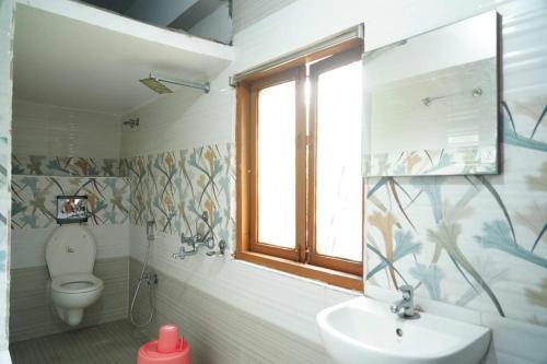 a bathroom with a toilet and a sink and a window at Sea side guest house vizag in Visakhapatnam