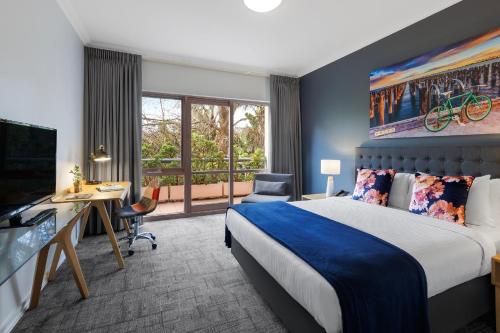 um quarto de hotel com uma cama, uma secretária e uma televisão em Kimberley Gardens Hotel, Serviced Apartments and Serviced Villas em Melbourne