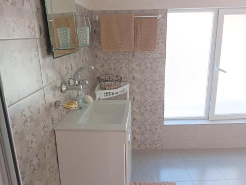 ein kleines Bad mit einem Waschbecken und einem Fenster in der Unterkunft При Старото пиано in Belogradtschik