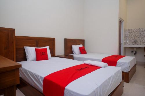 two beds in a room with red and white sheets at RedDoorz Syariah near Transmart Pabelan Solo in Kartosuro