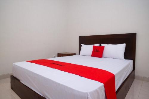 a bedroom with a bed with a red blanket on it at RedDoorz Syariah near Transmart Pabelan Solo in Kartosuro