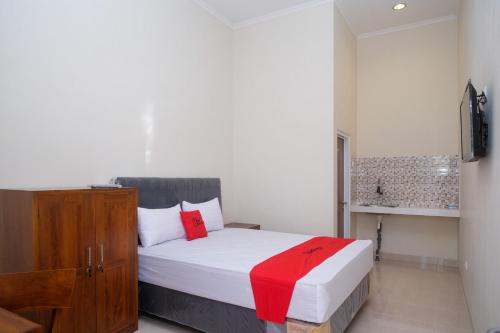 a bedroom with a bed with a red blanket at RedDoorz Syariah near Transmart Pabelan Solo in Kartosuro