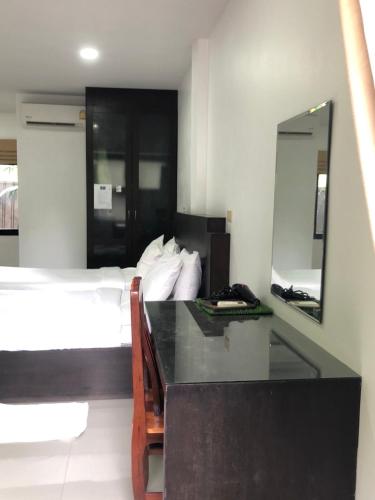 a bedroom with a bed and a desk with a mirror at พิชชาวรี รีสอร์ท in Ban Si Thep (2)