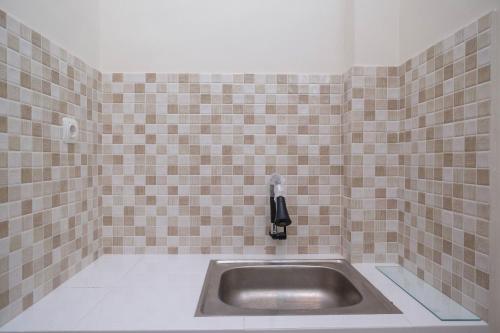 a sink in a tiled bathroom with a phone at RedDoorz Syariah near Transmart Pabelan Solo in Kartosuro