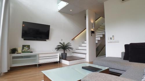 a living room with a couch and a tv on a wall at Ecoloft Jababeka Golf in Cikarang