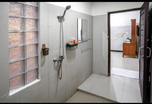 a white bathroom with a shower and a sink at Pondok Arya Kuta Villas by Kamara in Kuta