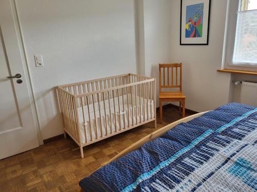 ein Schlafzimmer mit einem Kinderbett und einem Stuhl in einem Zimmer in der Unterkunft Les petits Rosiers in Tramelan
