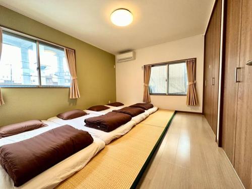 a row of beds in a room with windows at KOTORI HOUSE in Kyoto