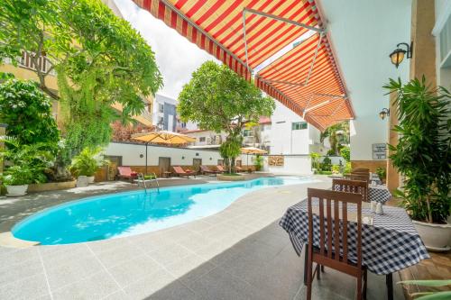 a swimming pool with a table and chairs next to a building at La Vintage Resort in Patong Beach