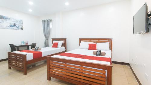 1 dormitorio con 2 camas y TV en la pared en RedDoorz RJs Bldg near Lyceum Gen Trias Cavite en General Trias