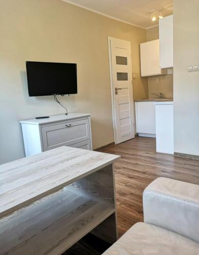 a living room with a table with a tv on the wall at Apartament Barcelona in Kłodzko