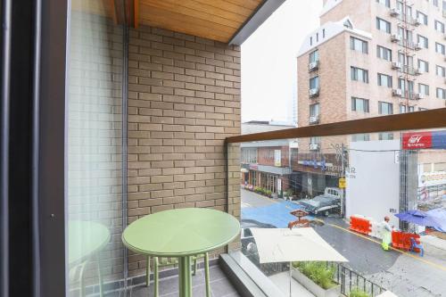 uma varanda com uma mesa verde e uma janela em Brown Dot Hotel Haeundae em Busan
