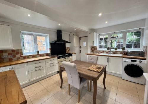 a kitchen with white cabinets and a wooden table at Comfy Room for ONE person - Netflix, Amazon Prime & Disney Plus in Bromley