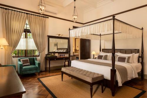 a bedroom with a canopy bed with a chair and a desk at The Grand Walawwa in Pinnawala