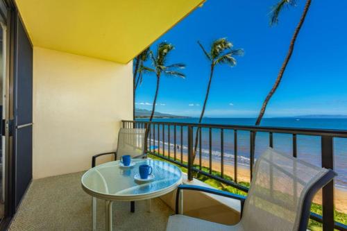 a balcony with a table and chairs and the beach at SUGAR BEACH RESORT, #326 condo in Kihei