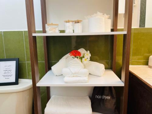 un estante con toallas y flores en el baño en Alux House, en Placencia Village