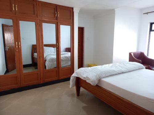 1 dormitorio con 1 cama y armario de madera en Didas Villa, en Arusha