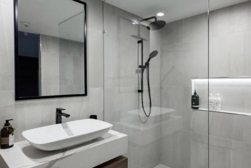 a white bathroom with a sink and a shower at Aquarius Luxury Apartment in Cairns