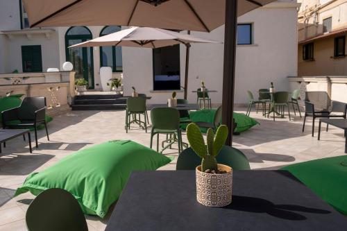 patio ze stołami i krzesłami z zielonymi parasolami w obiekcie Fiko Suite w mieście Roccella Ionica