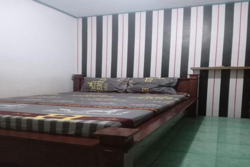 a bed in a room with a striped wall at OYO 92816 Ana Homestay in Banyuwangi