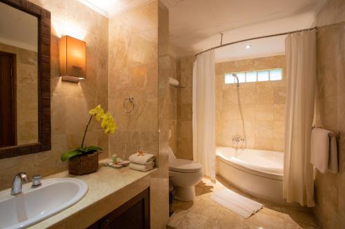 a bathroom with a tub and a sink and a toilet at Risata Bali Resort & Spa in Kuta