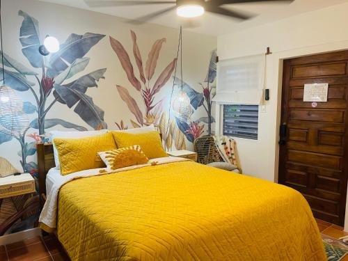 a bedroom with a yellow bed with a tropical wallpaper at Alux House in Placencia