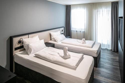 two beds in a hotel room with towels on them at Hotel Innsento - Health Campus Passau in Passau