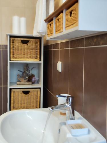 ein Badezimmer mit einem Waschbecken, einem Herd und Körben in der Unterkunft Apartmani Roko in Okrug Donji