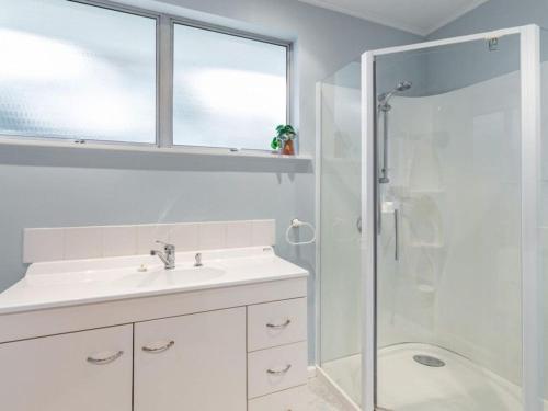 a white bathroom with a sink and a shower at The Airport Homestay House in Christchurch